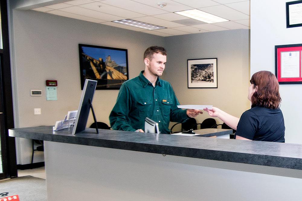 StrataTech front desk worker handing student a paper